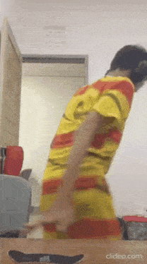 a man in a yellow and red striped shirt is standing in front of a table .