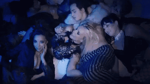 a group of women are laying on top of each other on a bed in a dark room .