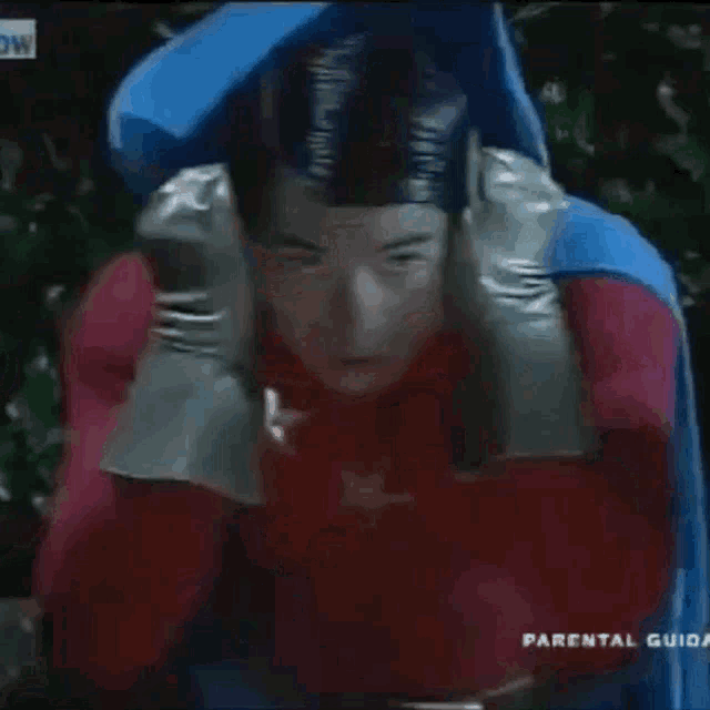 a man in a red and blue superhero costume is sitting on a blue chair .