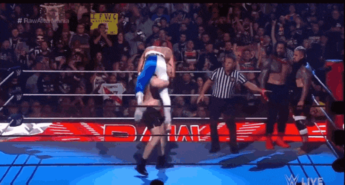 a wrestler is being lifted in the air by another wrestler during a match