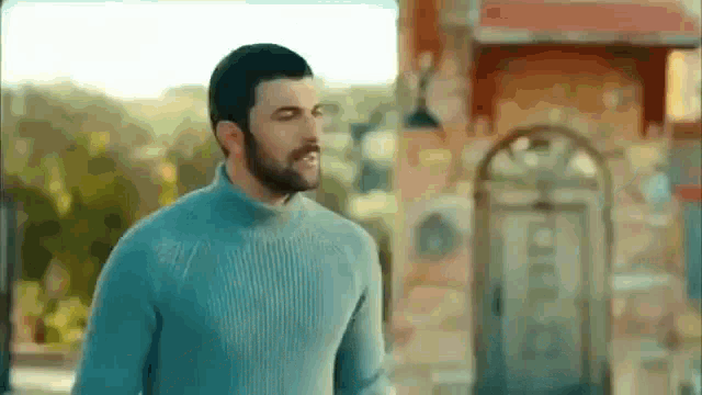 a man with a beard is wearing a blue sweater .