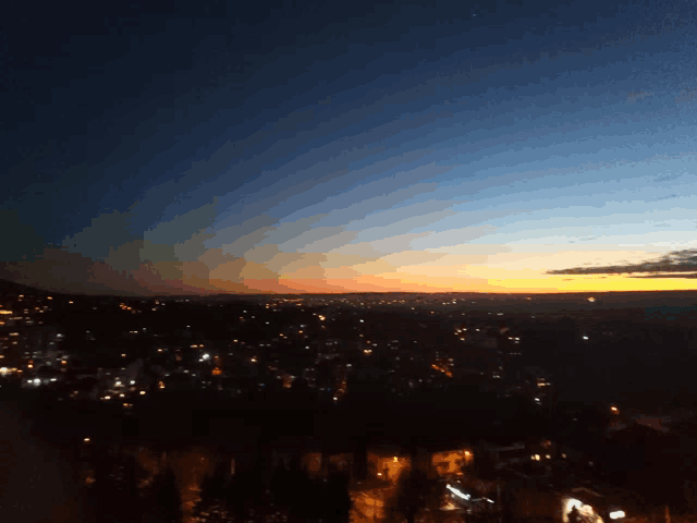 a sunset over a city with a few buildings lit up