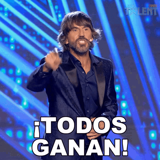 a man in a tuxedo stands on a stage and says todos ganan