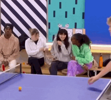 a group of people are playing ping pong on a blue table .