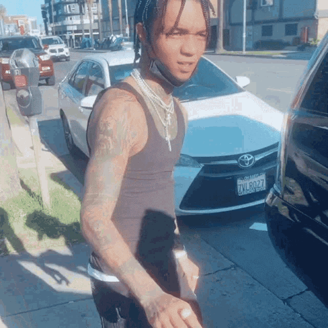 a man wearing a black tank top has a california license plate that says zvl8077