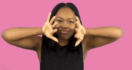 a woman in a black shirt is making a peace sign with her hands .