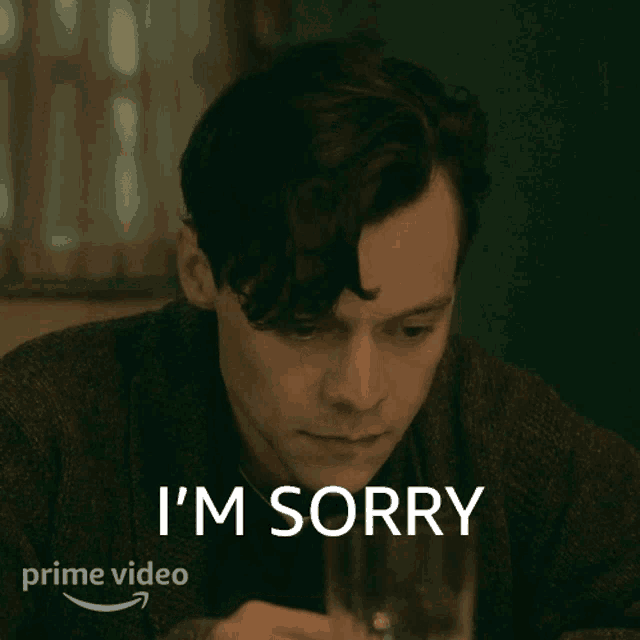 a man is sitting at a table with a glass and says i 'm sorry