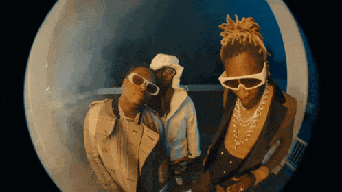 a group of three men wearing sunglasses and necklaces pose for a picture