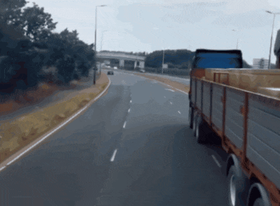 a truck is driving down a highway with a blue tarp on its back