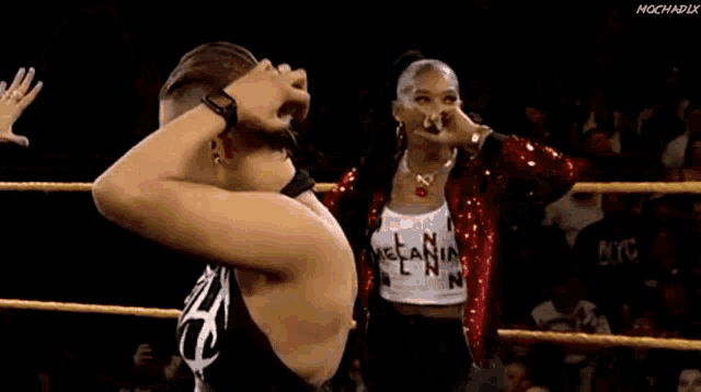 two women are standing next to each other in a wrestling ring and talking to each other .
