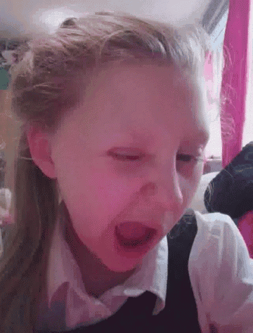 a little girl is making a funny face with her mouth open and her eyes closed .