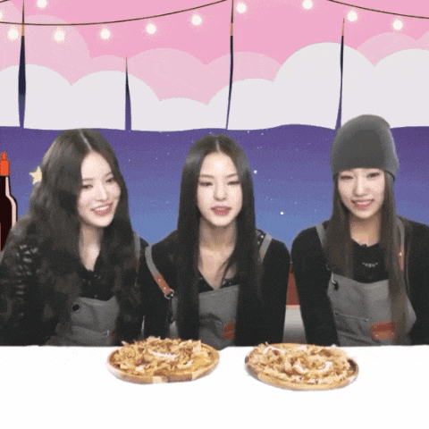 three young women are sitting at a table with pizzas on it