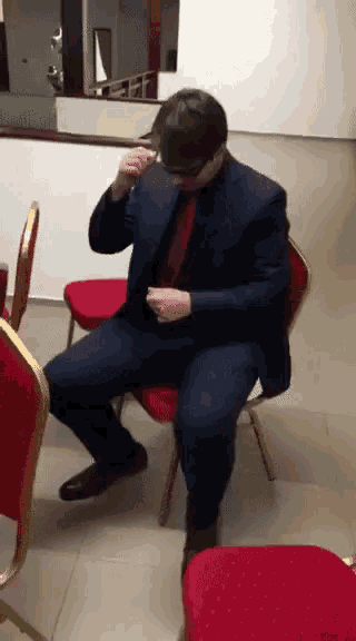a man in a suit is sitting in a red chair