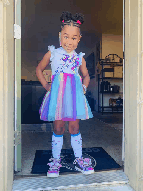 a little girl wearing a unicorn dress and socks stands in front of a door