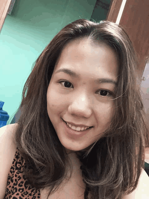 a woman in a leopard print top smiles for a picture