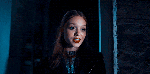 a woman with red lips is standing in a dark room .