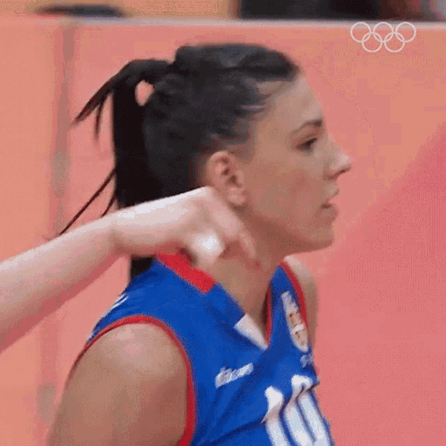 a woman wearing a blue red and white basketball jersey with a logo on the front