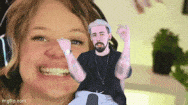 a woman is smiling while holding a picture of a man with a beard in front of her face .
