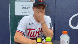 a baseball player is sitting at a table with his hand on his face .