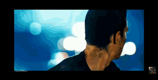 a man 's back is shown in a blurry photo with a blue background