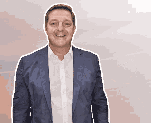 a man wearing a blue jacket and white shirt smiles