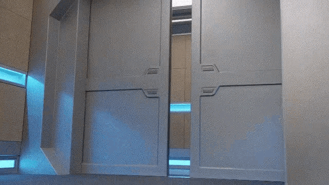 a woman in a blue shirt and black pants is walking through a doorway