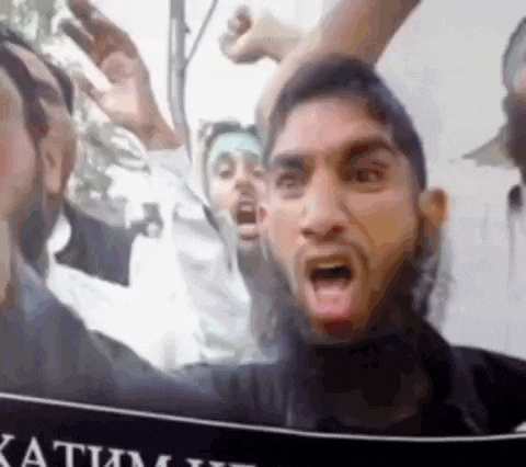 a man with a beard is screaming in front of a sign that says ' katim ' on it