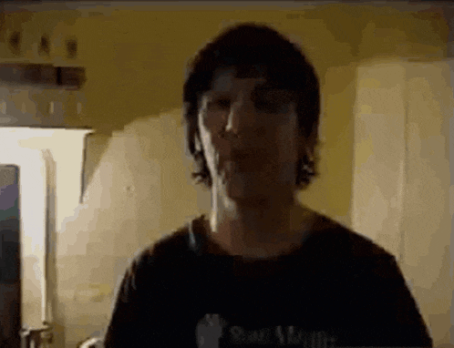 a man is standing in a kitchen with his mouth open and a black shirt on .