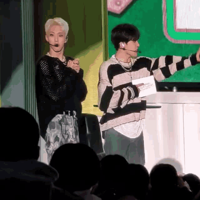 a man in a striped sweater stands next to another man with a microphone