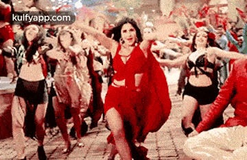 a woman in a red dress is dancing with a group of people .