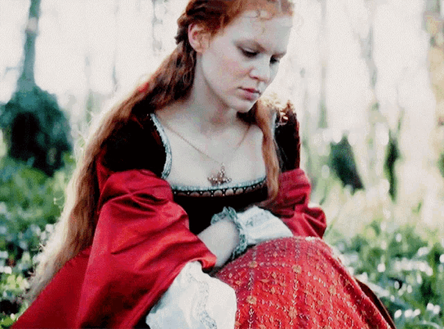a woman in a red dress is sitting in a field