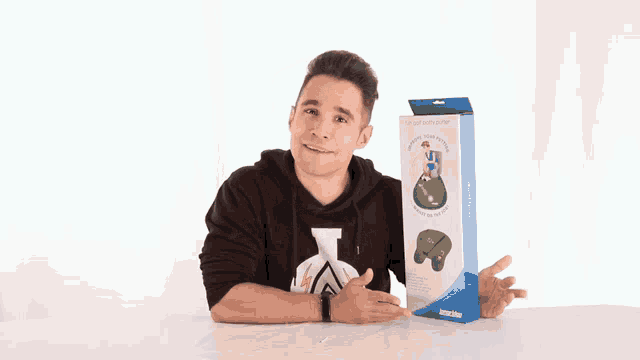 a man in a black hoodie is holding a box with a picture of a man on it