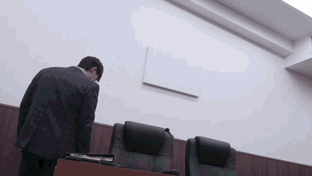 a man in a suit stands in front of a podium