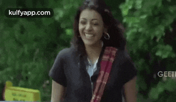 a woman is smiling while standing in front of a tree .