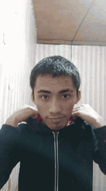 a young man in a black jacket is making a face