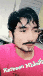 a man with a beard wears a pink shirt that says " kereen mblo " on it