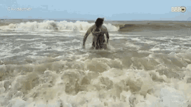 a man in a bikini is running through the waves on the beach .