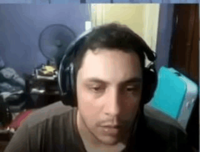 a man wearing headphones is sitting in front of a fan in a room .