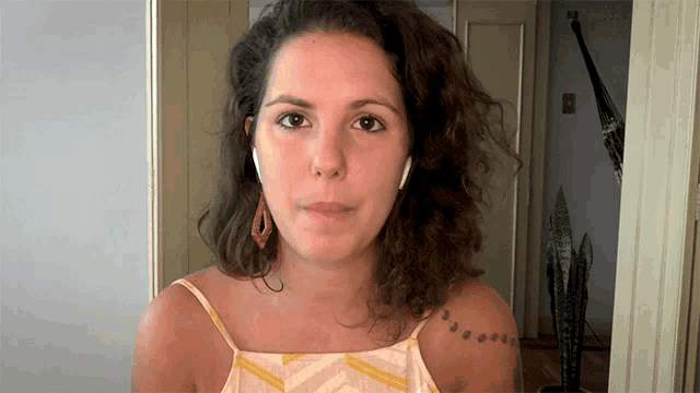 a woman with a tattoo on her shoulder is wearing earbuds