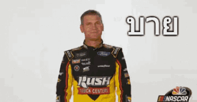 a man in a rush truck centers shirt is waving his hand