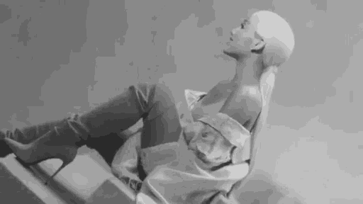 ariana grande is sitting on a chair wearing thigh high boots and a white shirt .