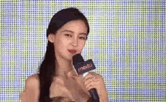 a woman is holding a microphone in front of a colorful screen .