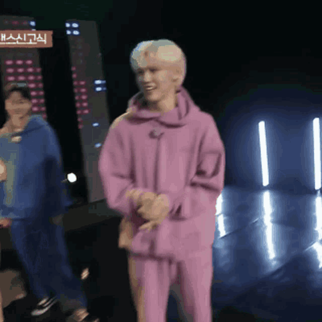 a man in a purple hoodie is standing in front of a sign that says hai
