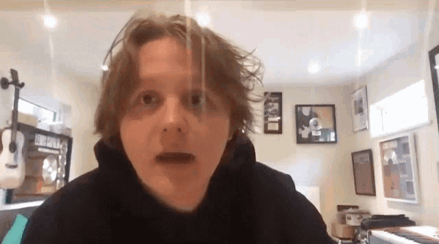 a young man with long hair is making a funny face while sitting in front of a piano .