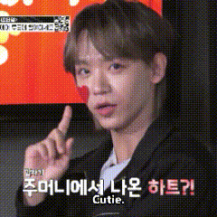 a young man with a red heart on his face is making a funny face while pointing up with his finger .