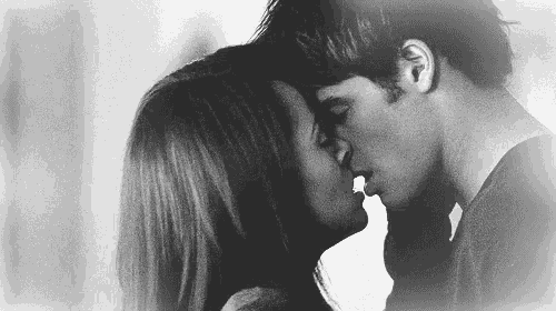 a black and white photo of a man and woman kissing each other .