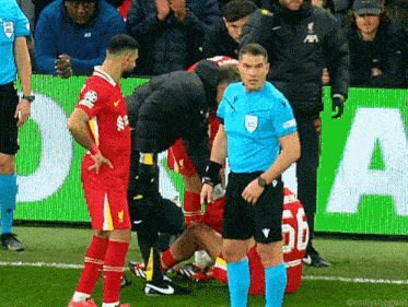 a soccer player with the number 56 on his jersey is being helped by a referee
