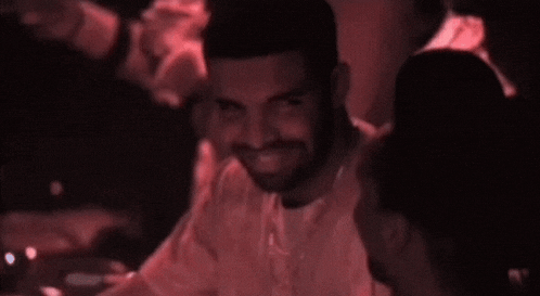 a man with a beard is sitting in a dark room with a red light behind him .