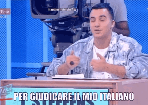 a man sitting at a desk with a sign that says per giudicare il mio italiano on it