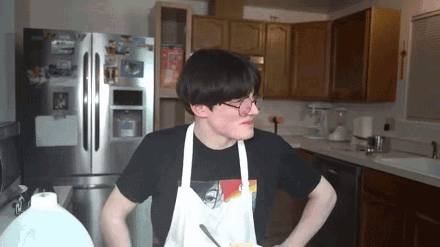 a man wearing an apron is standing in front of a refrigerator in a kitchen